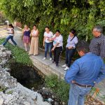 La síndica Paula Trade platica con vecinos de Ahuatlán frente a una zona de baches y fugas de agua